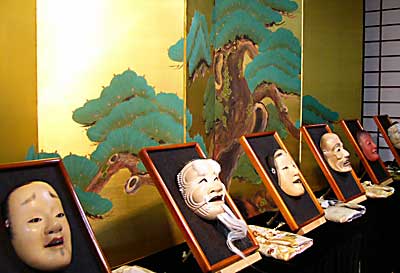マツを描いた金びょうぶの前に並ぶ富山さん制作の能面