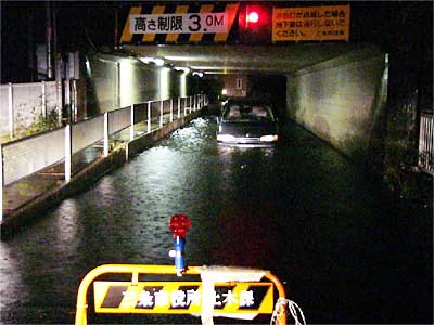 通行止めにした須頃3地内の石上大橋たもとの坂の下に取り残されて水につかる乗用車