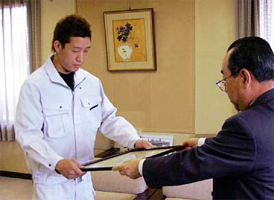 高橋燕市長から感謝状を受けとるトータルエレクトロニクスみつでん代表の大岩さん