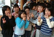 きねにくっついたもちをつまみ食いしてVサインの児童