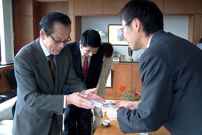 国定市長に善意を手渡す三条よってけ祭り実行委員会の箕輪実行委員長(左)