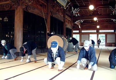 28日、本成寺で行われたすす払いで本堂の畳をタケの棒でたたく門前信徒