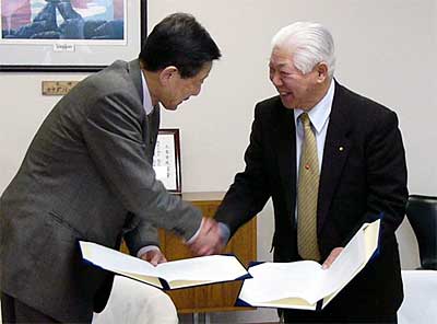 災害時における物資供給に関する協定書に調印し、笑顔で握手する高橋三条市長(左)と捧NPO法人コメリ災害対策センター理事長(右)