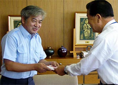 小林燕市長(右)に100万円を包んだのし袋を手渡す本間さん(左)