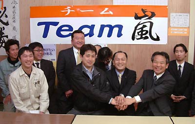 中央で握手する3人は左から馬場リーダー、嵐候補予定者、土田後援会長