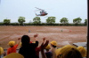 舞い上がるヘリコプターに校舎から手を振る児童