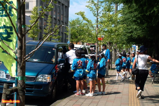 ふれ太鼓、猛暑のなか児童は保護者の車に分乗してそれぞれ次の会場へ