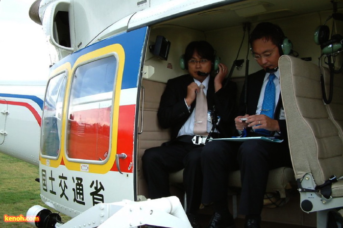 機内での会話用のヘッドホンとマイクをつけて搭乗する国定市長