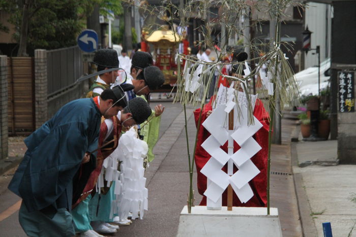 神輿行列の出発点に立てた御幣の前で星野宮司が祝詞