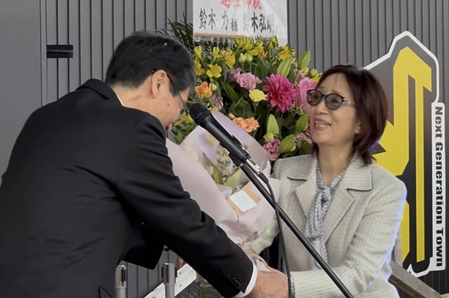 ネクストジェネレーションタウンで妻昭子さんに花束を手渡す鈴木市長