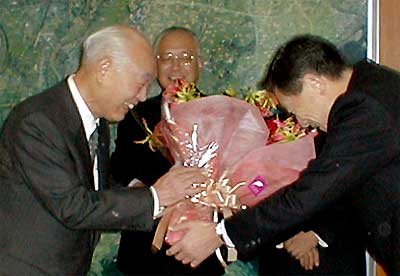 高橋市長から笑顔で花束を受ける永塚教育長(左)
