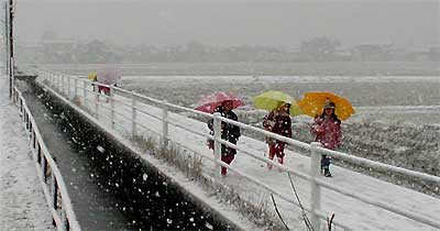 雪のなかをカラフルな傘をさして帰る児童
