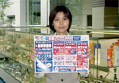お盆フェアー2002のちらしを手に県央地域地場産業振興センター職員