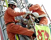 命綱をつけて神妙な表情ではしご車に搭乗する子どもたち
