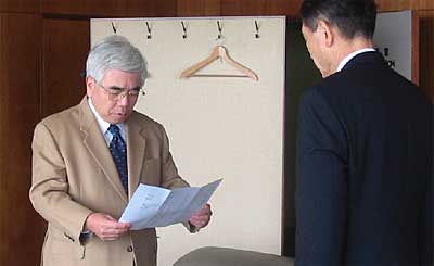 高橋三条市長に向かい寄付の目録を読み上げる坪井内科医院院長坪井正康さん(左)