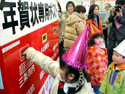 三条郵便局の年賀状差し出し式で年賀状専用ポストに年賀状を投かんする宝塔院幼稚園園児
