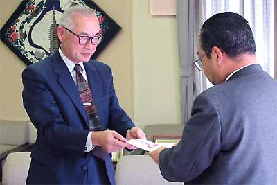 高橋燕市長に寄付を手渡す小田栄一さん（左）