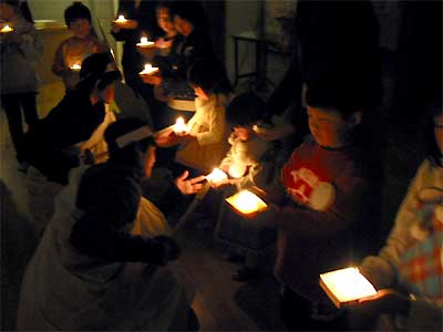 神妙な顔で火の守から分火を受ける子どもたち