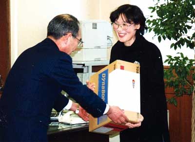 熊原三条郵便局長(左)から1等賞品のノートパソコンを受け取る山崎さん(右)