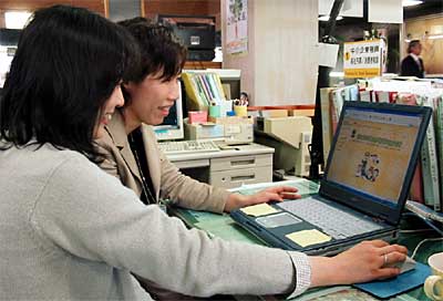 三条市勤労者福祉共済のホームページの更新作業をする市職員