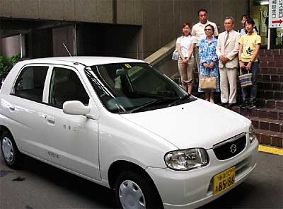三条市役所玄関前で寄付した軽自動車を前に記念撮影する川上さんら