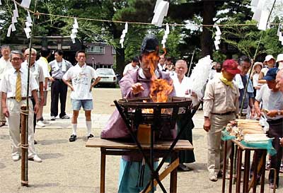 「はしの日」に行われた三条地区食品衛生協会三条支部のはし供養で神火にはしをくべる藤崎八幡宮宮司