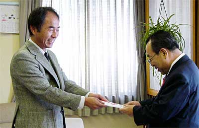 高橋燕市長に100万円を手渡す渡辺敏雄さん