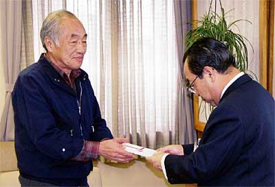 高橋燕市長（右）に共同募金への30万円を託す平田敏雄平田商事(株)社長（左）