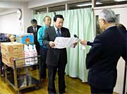 竹田助役に向かって目録を読み上げる加藤(株)角利産業社長