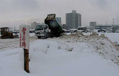 対岸に向かって雪の山がせり出す一心橋下流、五十嵐川左岸河川敷の雪捨て場