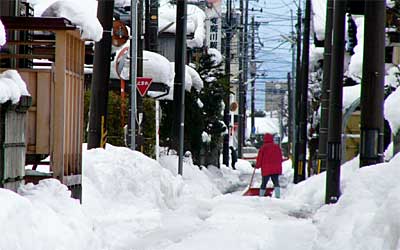 三条市横町地内の路地で雪かきに精を出す市民
