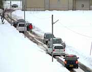 路肩の雪で道幅が狭くなり、車がすれ違えずににっちもさっちもいかなくなった上須頃地内の道路
