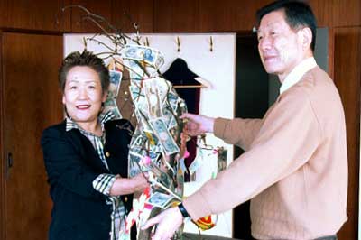 紙幣や硬貨が鈴なりのまゆ玉飾りを高橋市長(右)に手渡す五十嵐さん(左)