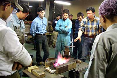 12日開かれた鍛冶職員育成講座で先輩鍛冶職人の実技を食い入るように見つめる受講者