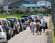 来場者の車の列と遠くにとめた車まで歩いて品物を持ち帰る人たち