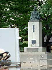 ごみの山の向こうに水害前と変わらない姿で立つ松尾与十郎の銅像