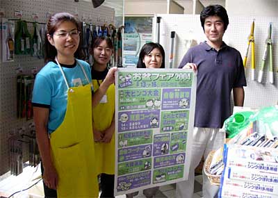 「お盆フェア2004」のポスターを手に来場を呼びかける県央地域地場産業振興センター職員