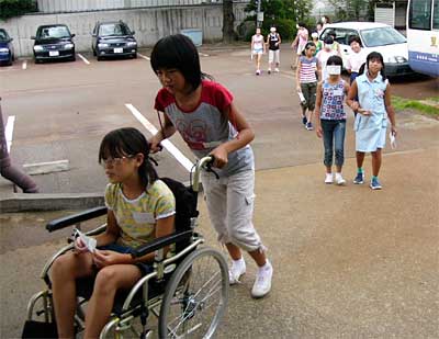 ボランティア活動体験キャンプで車いす体験とアイマスク体験を行う子どもたち