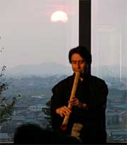 弥彦山に沈む夕日を背に尺八を吹く善養寺さん