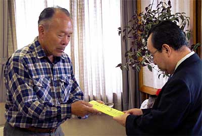 高橋燕市長(右)にゴルフコンペで募った三条市7・13水害義援金を手渡す(株)エムテートリマツの鳥部社長(左)