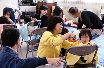 30日開かれた三条市大島公民館の子育てスキルアップ講座「おうちでヘアカット」で子どもの姿勢にあわせて髪を切るお母さん