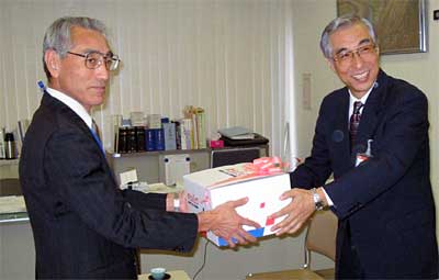 岩本三条市社会福祉協議会事務局長に使用済み切手を手渡す大矢三条郵便局長