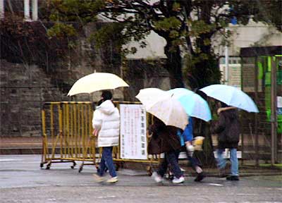 雪降るなか、三条市厚生福祉会館前で傘を差して歩く小学生
