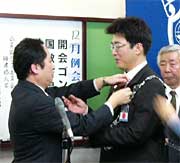 高橋次年度理事長(右)とバッジを交換する小池理事長(左)