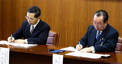 燕市のガス事業譲渡の仮契約調印式で仮契約書に調印する石井白根ガス(株)社長(左)と高橋燕市長(右)