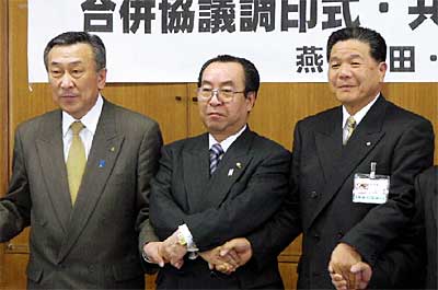 合併協議調印式後の共同記者会見で手をつなぐ左から泉吉田町長、高橋燕市長、小林分水町長