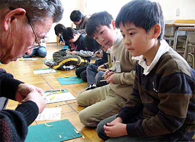 三条市立上林小学校で行われた竹とんぼ作りで、シルバー人材センター会員の小刀さばきを食い入るように見つめる3年生