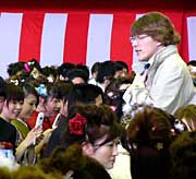 アトラクションのスマイリーキクチさんは新成人のなかに入って携帯電話の撮影にこたえる