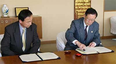 災害時における救援物資等の提供等に関する協定に調印する高橋三条市長(右)と本間三国コカ・コーラボトリング新潟支社長(左)