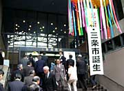 くす玉から「祝　新・三条市誕生」の垂れ幕が下がる庁舎正面玄関前